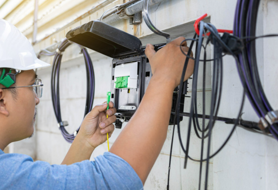 a professional cable installer wearing safety gear while carefully setting up cables in a residential home, showcasing the attention to detail and high-quality service provided by Insurance Company Worthington Ohio.